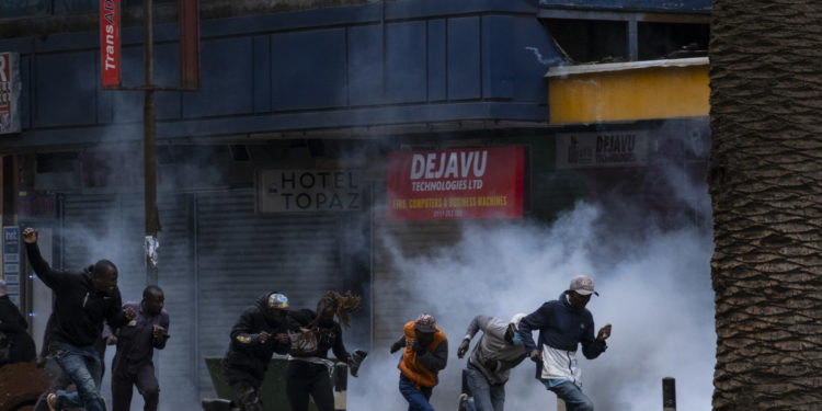 Protesters run fron tear gas at a planned demonstration called after a nationwide deadly protest against a controversial now-withdrawn tax bill left over 20 dead in downtown Nairobi, on June 27, 2024. Kenyans are preparing to take to the streets on Thursday for a white march the day after President William Ruto announced the withdrawal of the draft budget providing for tax increases, at the origin of a protest which foundered in murderous violence. (Photo by Kabir Dhanji / AFP)