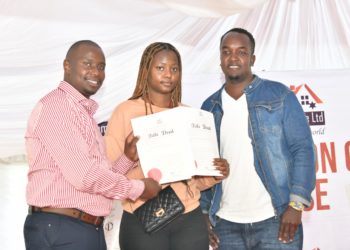 Nyota Njema real Estate Perminus Kariuki handing over a title deed to Rita Wambui and Moses Njuguna, when he issued more than 200 title deeds for Young Investors.