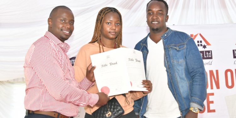 Nyota Njema real Estate Perminus Kariuki handing over a title deed to Rita Wambui and Moses Njuguna, when he issued more than 200 title deeds for Young Investors.