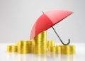 Gold coins and umbrella stacked on top of each other. insurance concept. Horizontal composition with copy space.