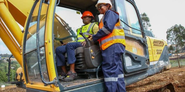 East Africa Breweries Limited Group Managing Director & CEO, Jane Karuku tries out the excavator by the operator Lydia Wahu during a ground breaking ceremony of a micro brewery set to be put up at the Ruaraka Headquarters.