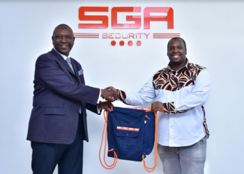 SGA Kenya Country Manager Lucas Ndolo (L) receives bags from Africa Collect Textiles General Manager Alex Musembi. The bags are made from old SGA guards uniforms in a bid to promote a clean environment