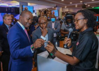 Safaricom M-Pesa Segment Marketing, Sheila Chenye (Right), demonstrates how a braille smart watch works to Cabinet Secretary, Ministry of ICT, Innovation & Youth Affairs, Hon. Joseph Mucheru (Left) and Chief Executive Officer, Safaricom PLC, Peter Ndegwa (Center) during the FinTech Innovation Week event at the Michael Joseph Center in Nairobi.