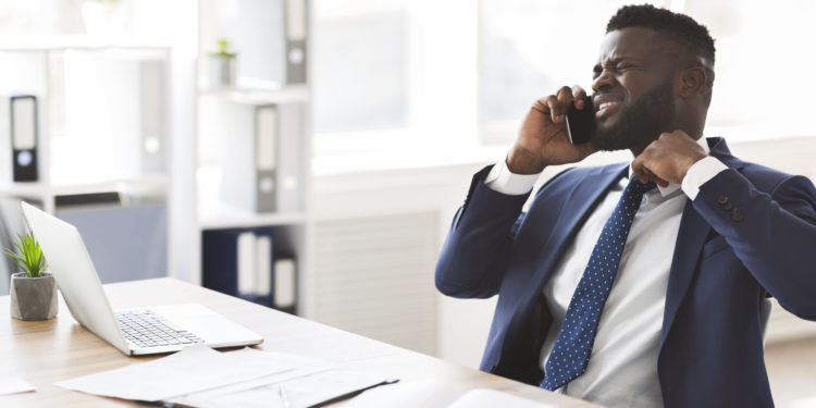 Stressed young african american manager talking by phone with colleagues in office, holding tie, copy space