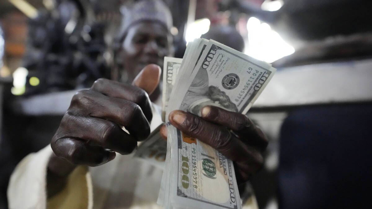 A man counts U.S. $100 bills at the craft and art market in Lagos, Nigeria, on Wednesday, Aug. 16, 2023. Across the developing world, many countries are fed up with America's dominance of the global financial system — and especially the power of the dollar. (AP Photo/Sunday Alamba)