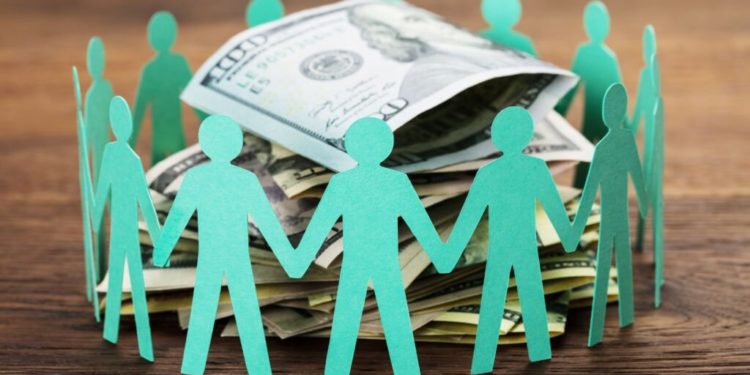 Crowdfunding Concept. Paper Cut Out Human Figures Around The Stack Of Hundred Dollar Bills